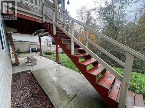 A red staircase with a white railing is in front of a house.