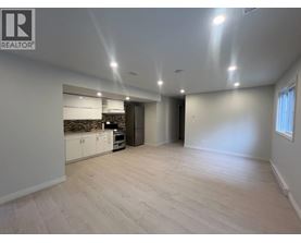 A spacious room with a kitchen area and a door leading to another room.