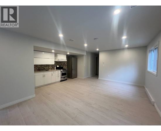 A spacious room with a kitchen area and a door leading to another room.
