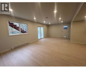 A spacious room with wooden flooring and a large window.