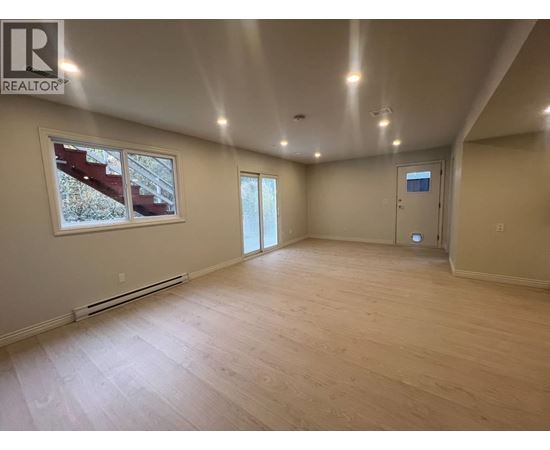 A spacious room with wooden flooring and a large window.
