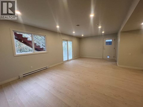 A spacious room with wooden flooring and a large window.