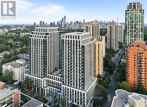 A tall building with a balcony on the 10th floor is in the foreground of a cityscape.