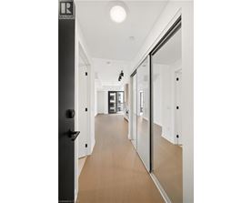 A long hallway with a black door on the left and a glass door on the right.