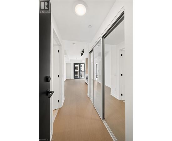 A long hallway with a black door on the left and a glass door on the right.