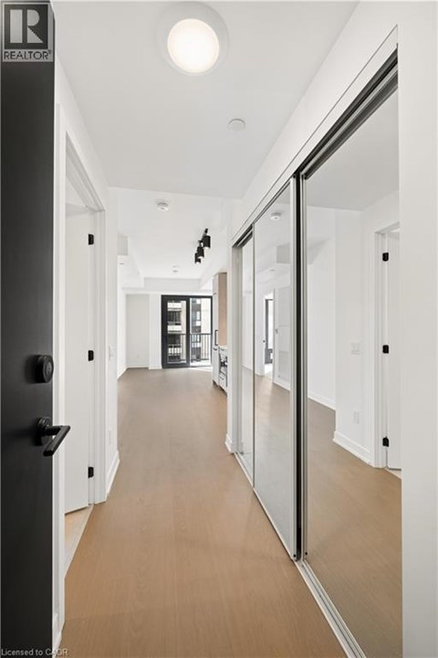 A long hallway with a black door on the left and a glass door on the right.