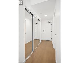 A hallway with white walls and wood flooring.