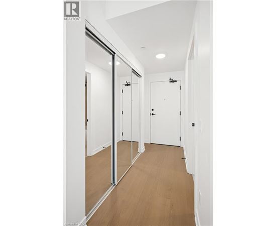 A hallway with white walls and wood flooring.