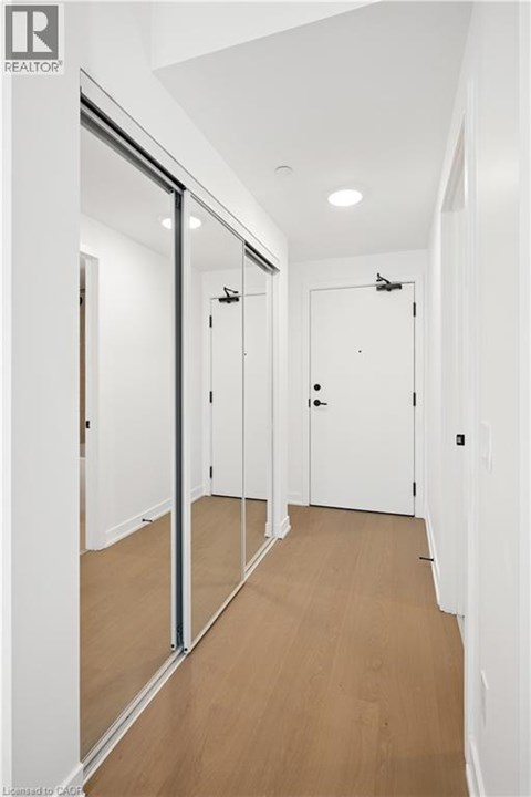 A hallway with white walls and wood flooring.