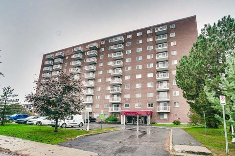 A tall apartment building with a red awning at the entrance.