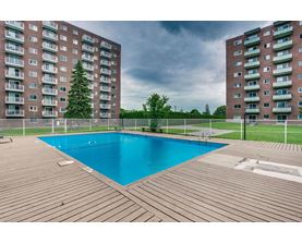 A pool in a backyard surrounded by two apartment buildings.