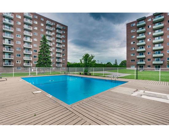 A pool in a backyard surrounded by two apartment buildings.