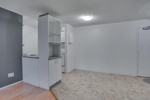 A kitchen with white cabinets and a grey wall.