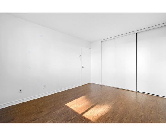 A room with a white wall and a wooden floor.