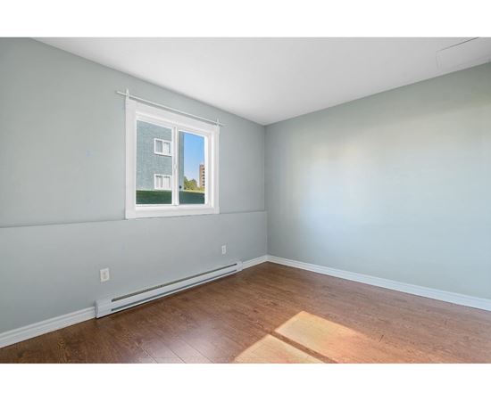A room with a window showing a building outside.