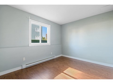 A room with a window showing a building outside.