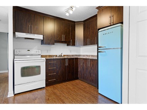 A kitchen with a white oven and a blue fridge.