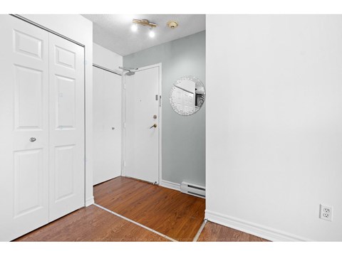 A hallway with a white door on the left and a white door with a mirror above it on the right.