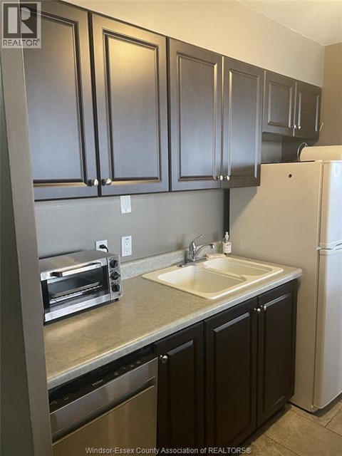 A kitchen with dark brown cabinets and a white refrigerator.