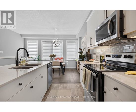 A modern kitchen with white cabinets and black appliances.