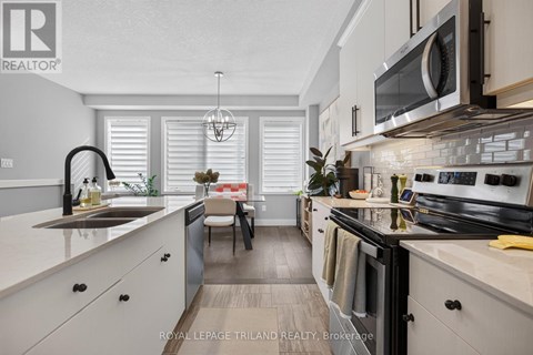 A modern kitchen with white cabinets and black appliances.
