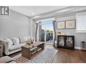 A living room with a white couch, a wooden coffee table, and a large window with a view of the outside.