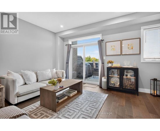A living room with a white couch, a wooden coffee table, and a large window with a view of the outside.