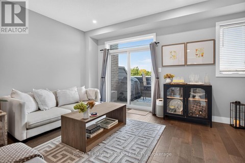 A living room with a white couch, a wooden coffee table, and a large window with a view of the outside.