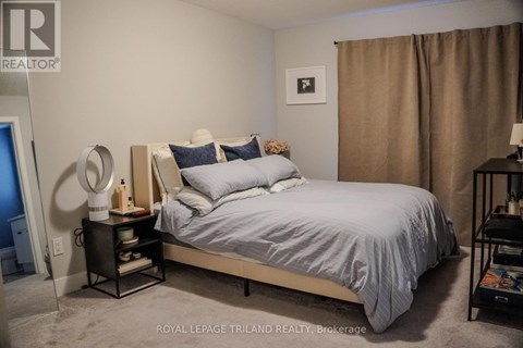 A bedroom with a bed, nightstand, and lamp.
