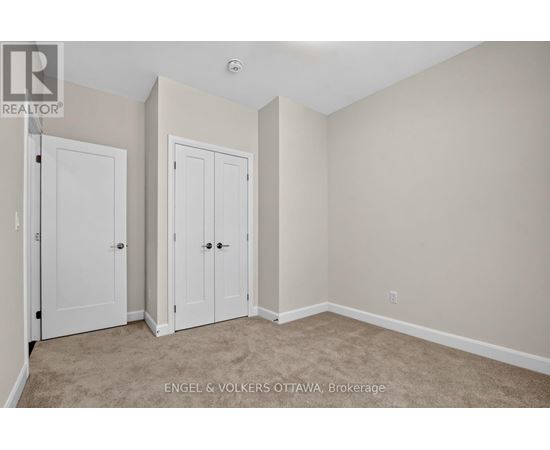 A bedroom with two doors and a carpeted floor.