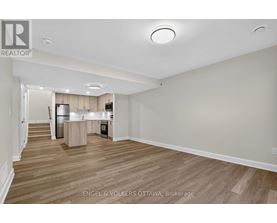 A spacious, empty room with wooden flooring and white walls.