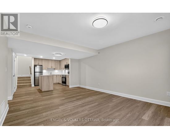 A spacious, empty room with wooden flooring and white walls.