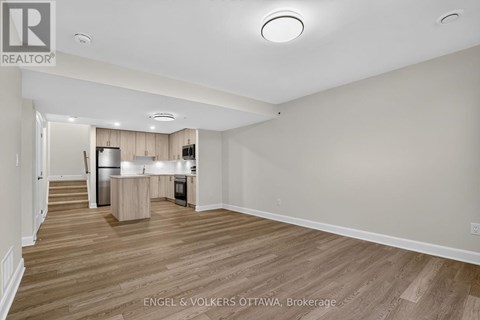 A spacious, empty room with wooden flooring and white walls.