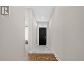 A hallway with a black door and a tiled floor.