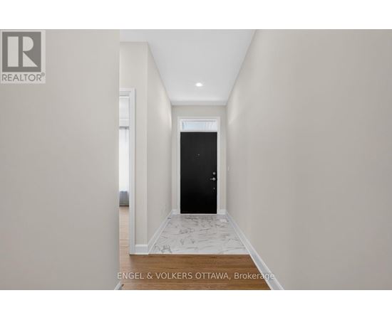 A hallway with a black door and a tiled floor.