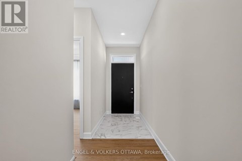 A hallway with a black door and a tiled floor.