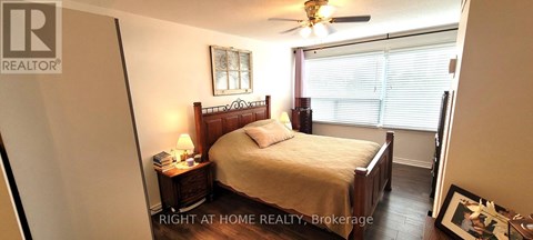 A bedroom with a bed, nightstand, and window.