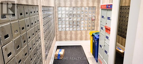 A room with a wall of mailboxes and a small rug on the floor.
