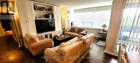 A living room with a couch, chairs, and a television.