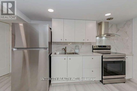 A kitchen with white cabinets and a stainless steel refrigerator.