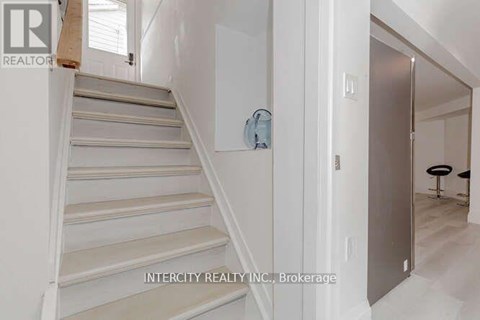 A staircase in a house with a logo of Intercity Realty INC. Brokerage on the wall.
