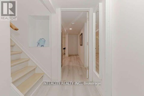 A hallway with white walls and a wooden floor.