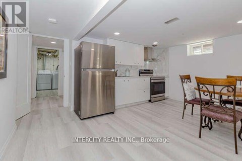 A kitchen with a stainless steel refrigerator and a dining table with chairs.