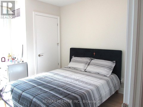 A bedroom with a bed, nightstand, and door.