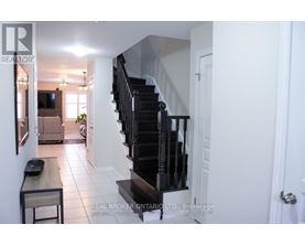 A hallway with a staircase and a table with a plant on it.