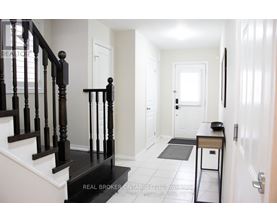 A hallway with a black staircase and white walls.