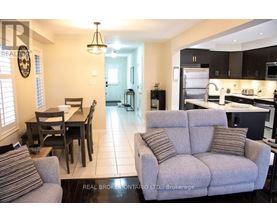 A living room with a grey couch and a dining table with chairs.