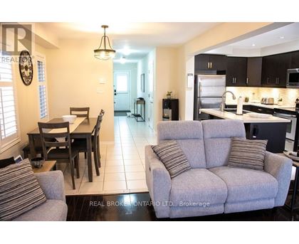 A living room with a grey couch and a dining table with chairs.