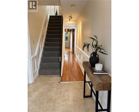 A hallway with a staircase and a table with a vase and a book on it.