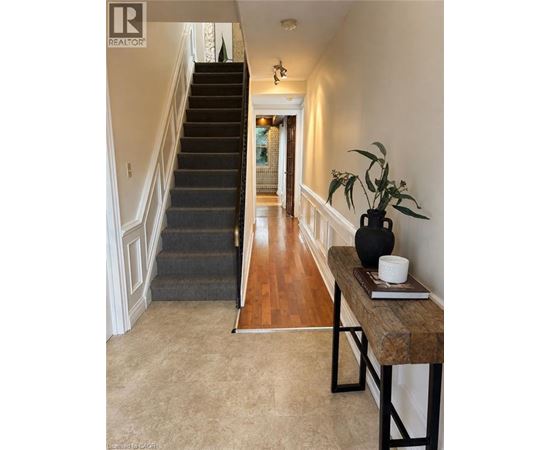 A hallway with a staircase and a table with a vase and a book on it.